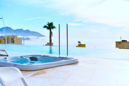 a swimming pool with a hot tub and a palm tree at Benidorm Sunset Cliffs in Benidorm