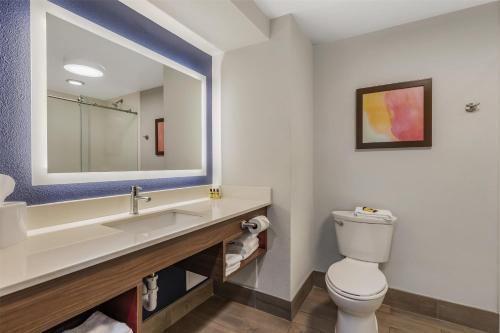 a bathroom with a toilet and a sink with a mirror at Best Western Plus Lexington Inn in Lexington