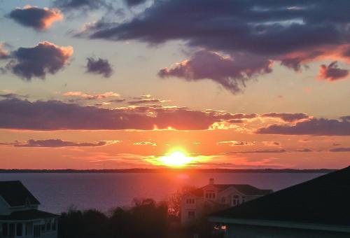 a sunset over a body of water with buildings at De-Duck-Tible - D0318 in Duck