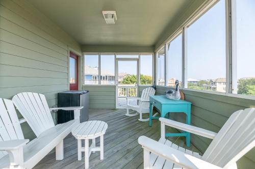 a porch with white chairs and a blue table at De-Duck-Tible - D0318 in Duck