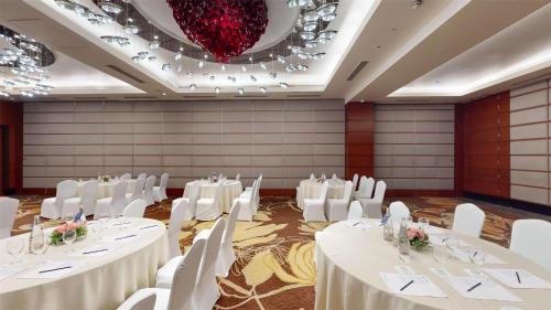 a banquet hall with white tables and chairs and a chandelier at Radisson Blu Hotel, Nagpur in Nagpur
