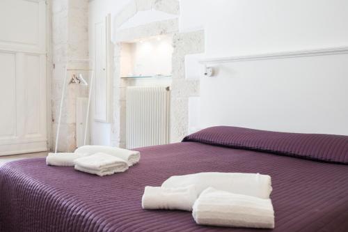 Una cama morada con toallas blancas encima. en CASA FLAMì 5, en Ostuni