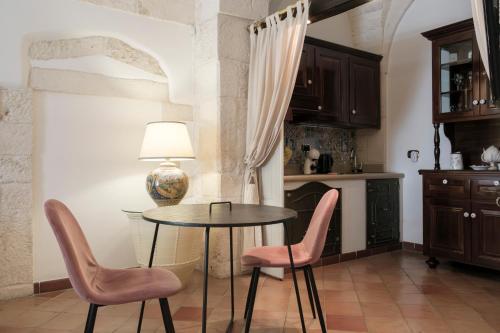 cocina con mesa y 2 sillas rosas en CASA FLAMì 5, en Ostuni