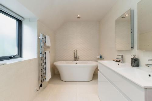 a white bathroom with a tub and two sinks at Waterfield House B&B in Dorchester