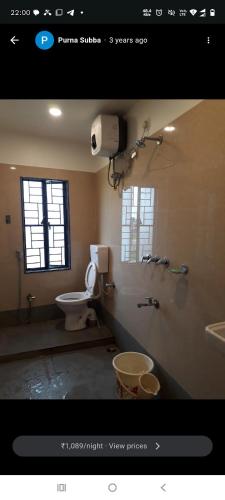 a bathroom with a toilet and a window at Maa Tara Lodge in Bāghdogra