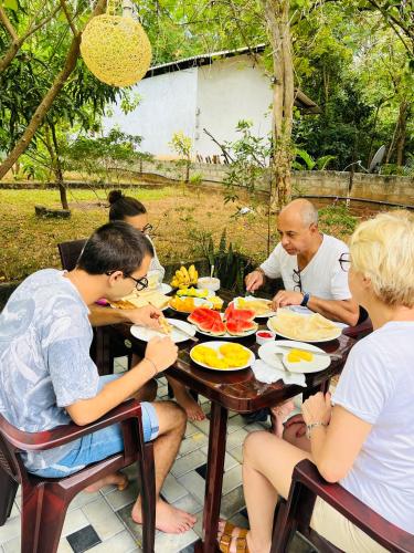 a group of people sitting at a table eating food at Mashi's Villa in Sigiriya