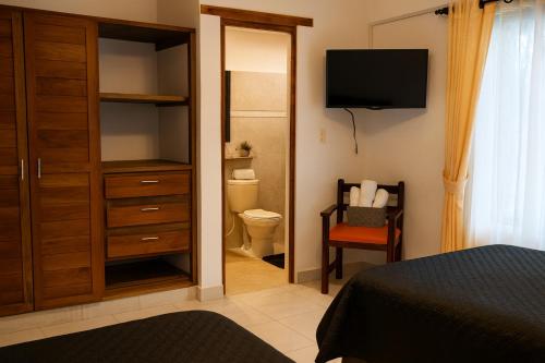 a bedroom with a closet and a toilet and a television at Habitaciones con baño privado en cabaña estilo hostel in Villa de Leyva