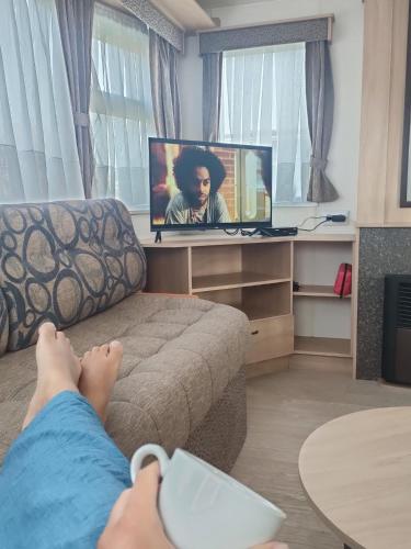 a person laying on a couch watching a tv at Havana De Luxe Bredene in Bredene