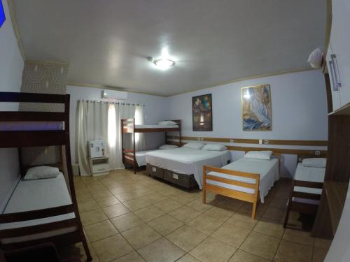 a bedroom with two beds and a table and chairs at POUSADA EVELINA in Foz do Iguaçu