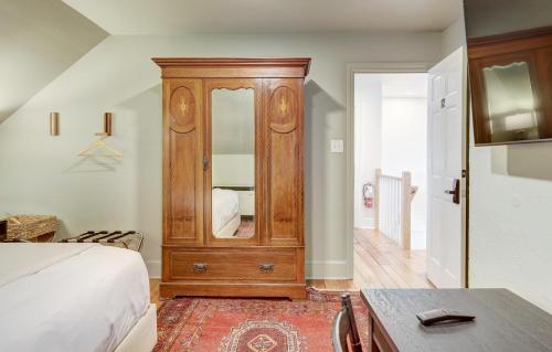 a bedroom with a wooden cabinet with a mirror at The 200 South St - King Rm 12 in Charlottesville