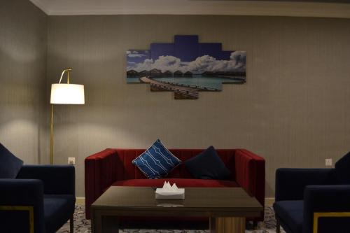 a living room with a red couch and a table at فندق الشهباء الفيحاء Hotel Al Shahba Al Faiha Jeddah in Jeddah