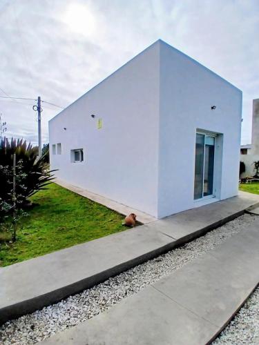a dog sitting in front of a white house at Casa con jardín Las Marías 1 in Miramar