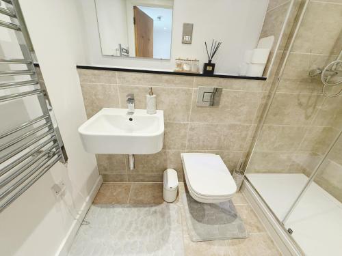 a bathroom with a sink and a toilet and a shower at Fast WiFi, Free Netflix 2 Bedroom Penthouse with Large Balcony in Slough