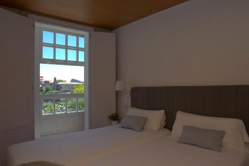 a bedroom with a white bed and a window at Pensión O Xardin de Julia in Santiago de Compostela