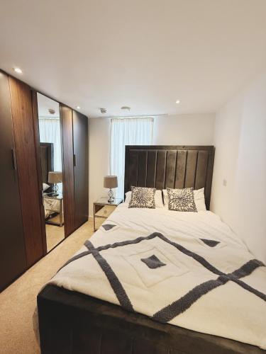 a bedroom with a large bed with a wooden headboard at Fast WiFi, Free Netflix 2 Bedroom Penthouse with Large Balcony in Slough
