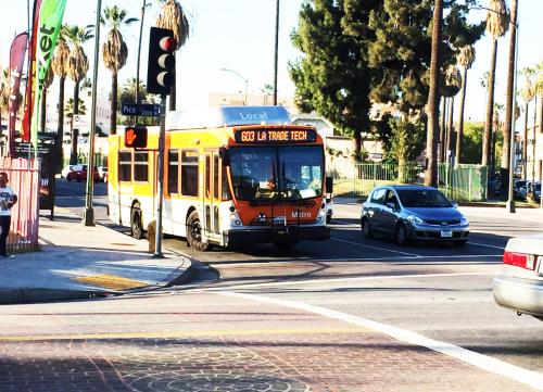 a bus is driving down a city street with cars at Hollywood Stay in Los Angeles