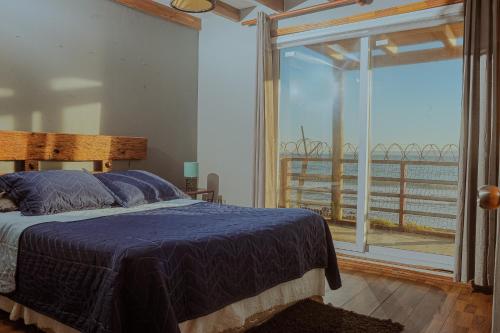 a bedroom with a bed and a large window at Cabañas Bordemar Habitaciones para 2 y 3, Cabañas para 4 y 5 huéspedes in Tomé