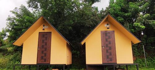 a small house with two doors in the grass at Mount Camp in Marayoor