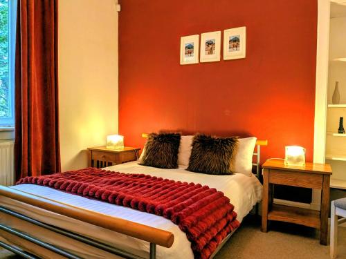 a bedroom with a bed with a red wall at Scottish Highland Cottage Tyndrum Upper Station in Crianlarich