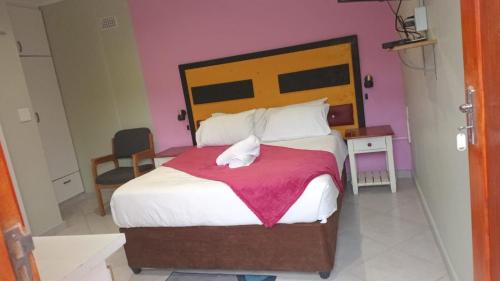 a bedroom with a large bed with a pink wall at Emampingeni lodge in Bizana