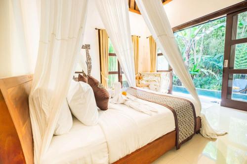 a bedroom with a bed with a canopy at villa restu 2 in Ubud