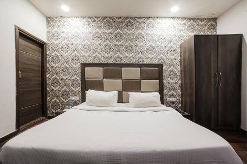 a bedroom with a large white bed and a wall at Townhouse Hollywood Heights in Amritsar