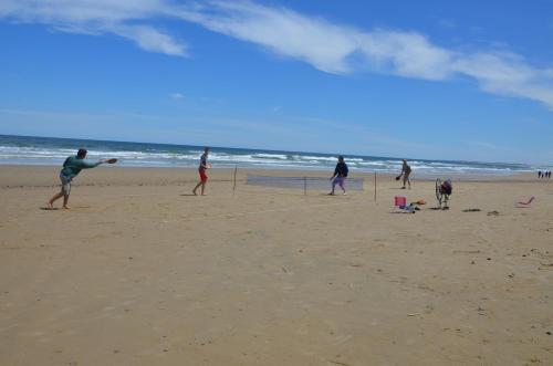 a group of people playing soccer on the beach at La Brújula Hostel in La Paloma