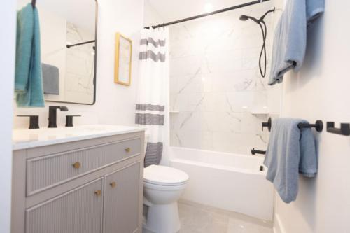 a white bathroom with a sink and a toilet and a tub at Awesome 3 bdr,1 bath condo,1fl,2min walk to beach in Wildwood