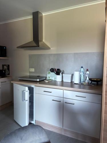 a kitchen with white cabinets and a white refrigerator at Studio Les Champs in Baelen