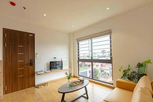 a living room with a couch and a table and a window at LUMI West Lake Hotel in Hanoi