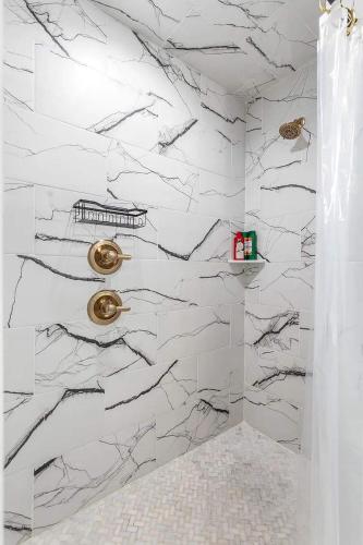 a bathroom with white marble walls and gold fixtures at Gilead Grand Lake Family Retreat in Grove