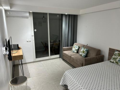 a bedroom with a bed and a couch and a television at Studio Tartane in La Trinité