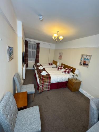 a hotel room with a bed and two chairs at Rossdene House in Blackpool