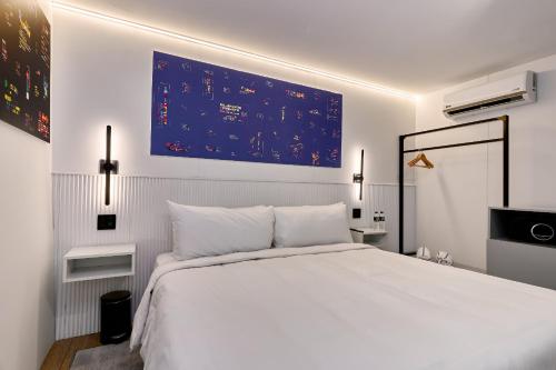 a bedroom with a white bed and a blue board on the wall at Casa Guogu by AmazINN Places 2f in Panama City