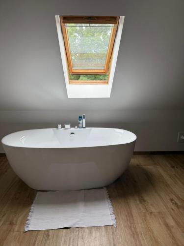 a white bath tub in a bathroom with a window at Saniertes Penthouse im Park am Goitzschesee in Bitterfeld