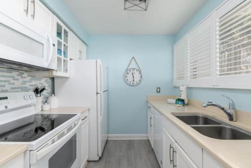 a kitchen with white cabinets and a sink and a clock at Seascapes 3061 - Roomy Villa Close To Beach in Hilton Head Island