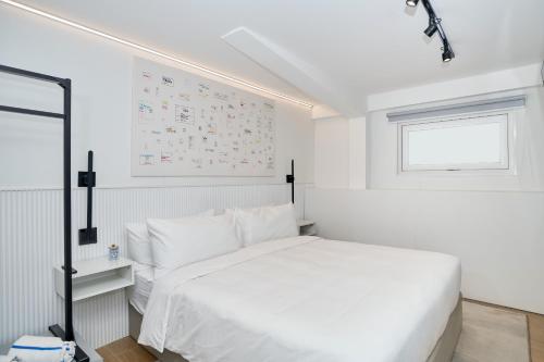 a white bedroom with a white bed and a window at Casa Guogu by AmazINN Places 3f in Panama City