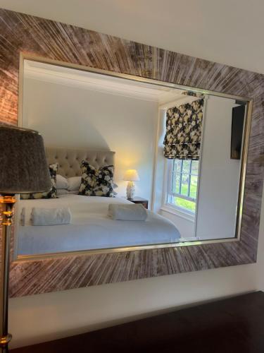 a mirror reflecting a bedroom with a bed and a window at Scarborough Hill Country Inn in North Walsham