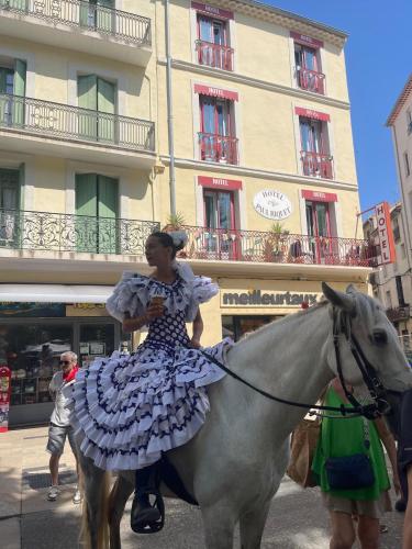 a woman in a dress riding a horse on a street at Hôtel Paul Riquet in Béziers