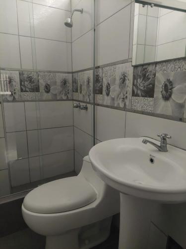 a white bathroom with a toilet and a sink at Hospedaje El Jardín in Lima
