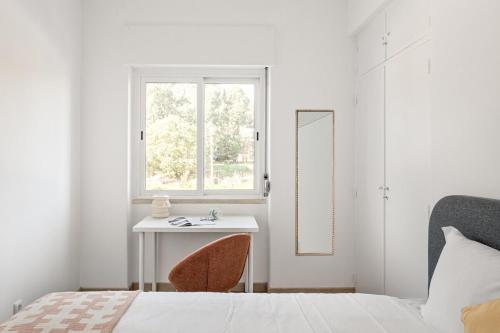 a bedroom with a bed and a table and a window at GuestReady - Striking flat in Benfica in Lisbon