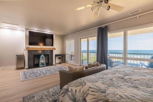 sypialnia z łóżkiem, kominkiem i telewizorem w obiekcie WEL307 Downs by the Sea. Oceanfront, Luxury Condo, Saltwater Pool, Elevator! w mieście Kill Devil Hills