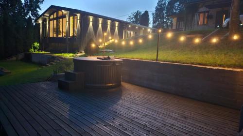 a wooden deck with a building with lights on it at White Hill's Nest in Zvejniekciems