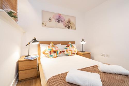 a white bedroom with a bed and two lamps at Farringdon Apartments in London