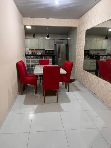 a dining room with a table and red chairs at Casa in Ananindeua