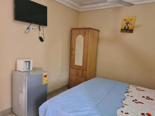 a bedroom with a refrigerator and a tv on the wall at Crystal Rock Hotel in Teiman
