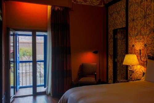 a bedroom with a bed and a window and a chair at Palacio del Inka, a Luxury Collection Hotel, Cusco in Cusco