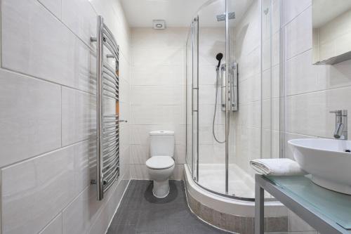 a bathroom with a shower and a toilet and a sink at Farringdon Apartments in London