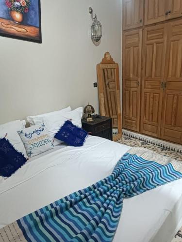 a white bed with a blue and white blanket on it at Gite Marbie maison rurale, une expérience naturelle unique, au coeur du moyen atlas, Maroc in Kasba Tibouda