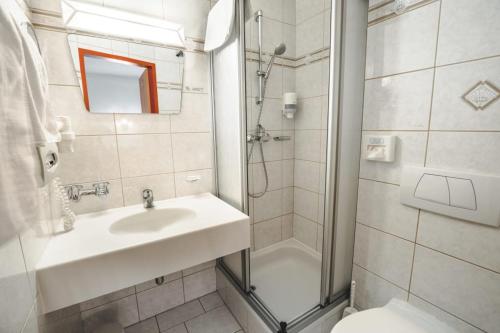 a bathroom with a sink and a shower and a toilet at Hotel Metzgerwirt in Kirchberg in Tirol